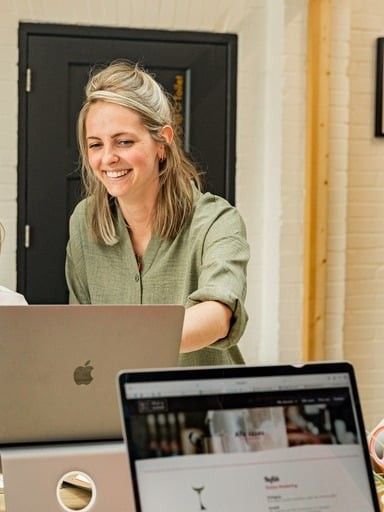 Ruth, lachend achter haar laptop in de studio
