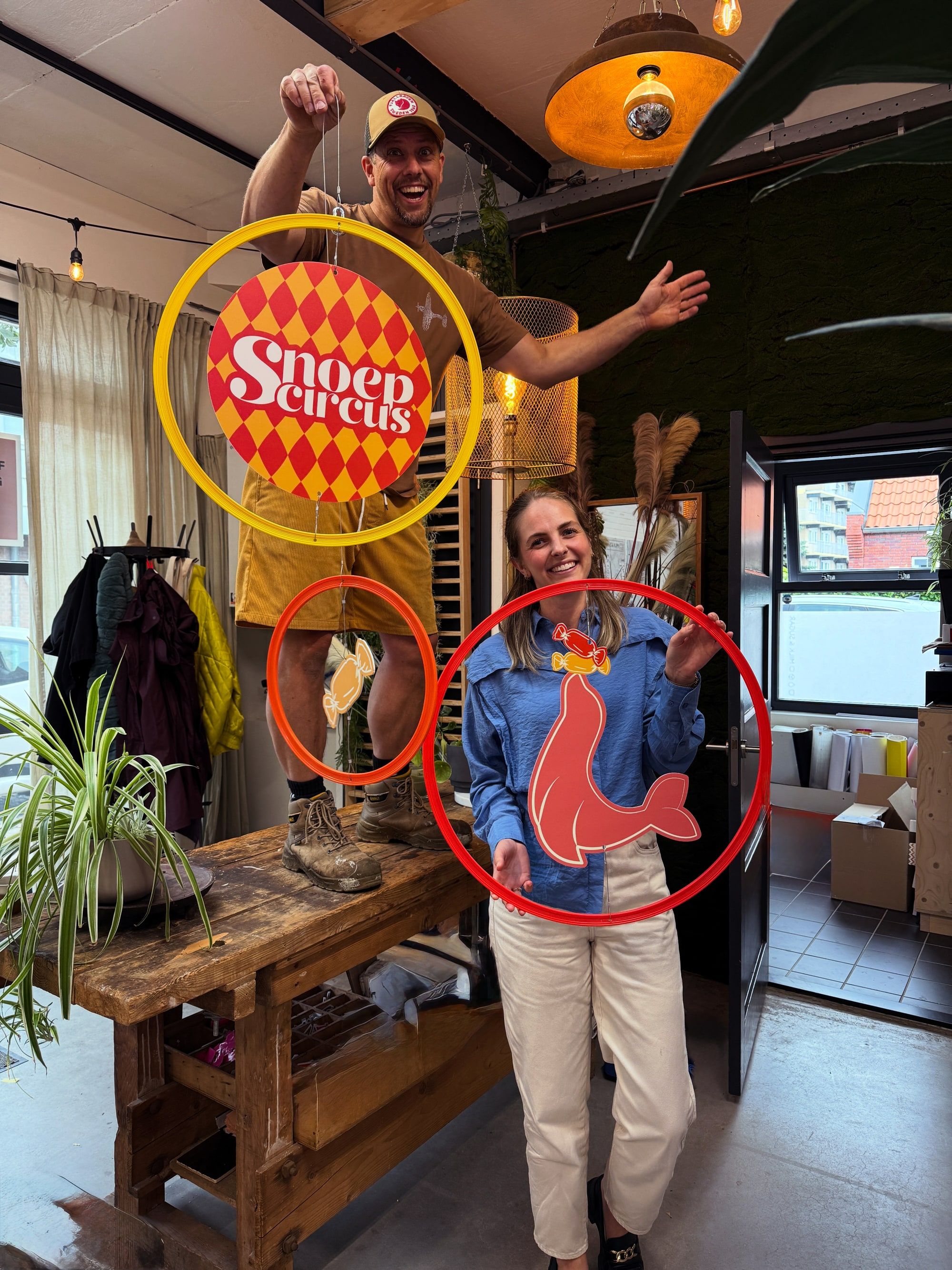 Thijs en Ruth hangen circusringen op met het Snoepcircus-logo en een zeehond-illustratie